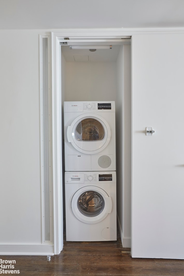 laundry room with estacked washer and dryer and dark wood-style floors
