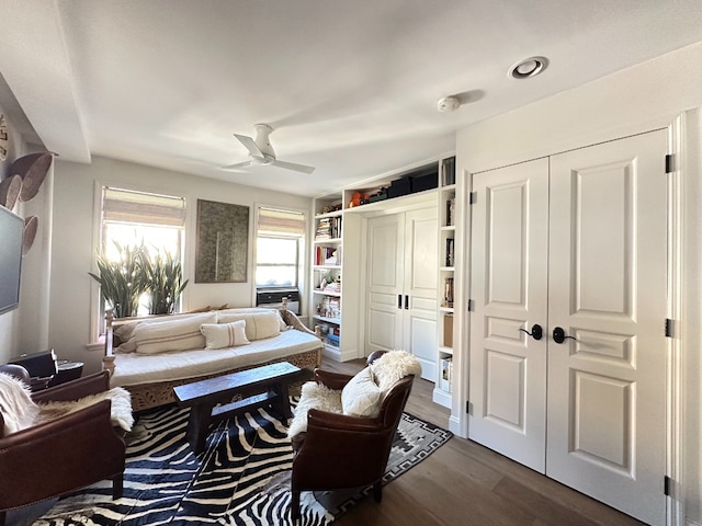 living area with dark wood-type flooring and a ceiling fan