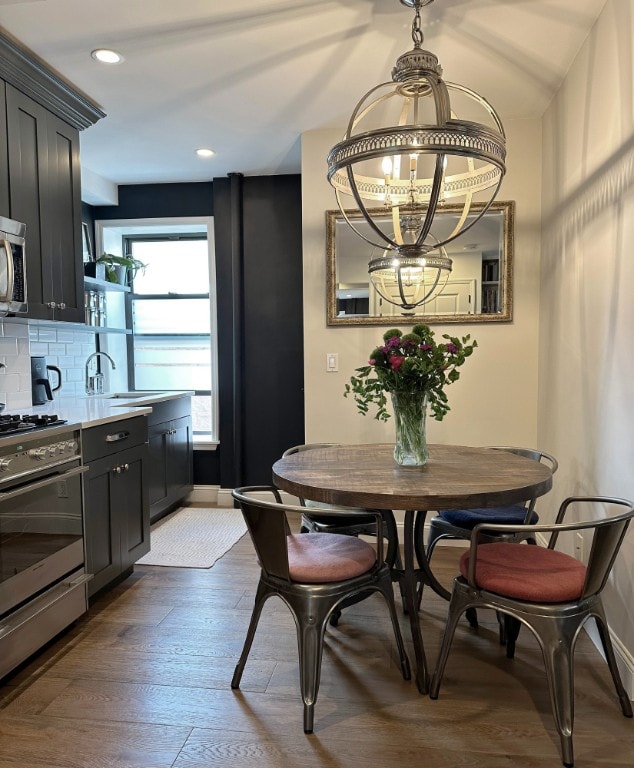 dining room with an inviting chandelier, baseboards, wood finished floors, and recessed lighting