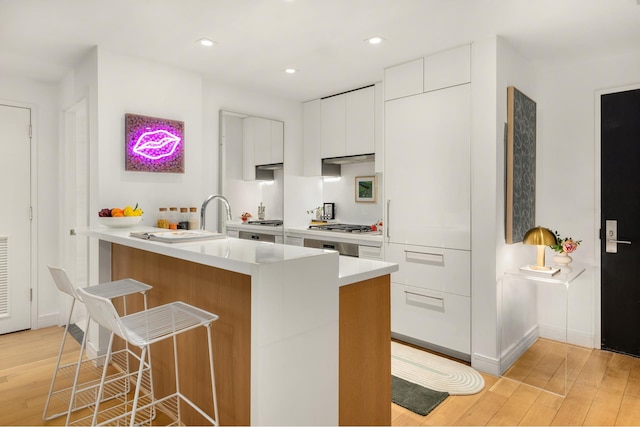 230 E 20th St Unit 13, New York City, NY 10003 - kitchen featuring light wood-style floors, modern cabinets, a breakfast bar, white cabinetry, and light countertops
