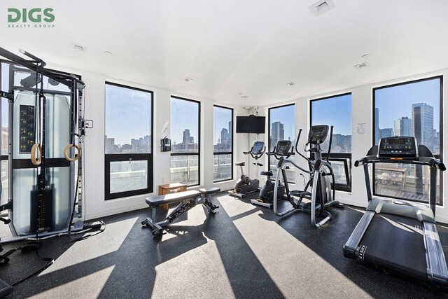 workout area featuring floor to ceiling windows, visible vents, and baseboards