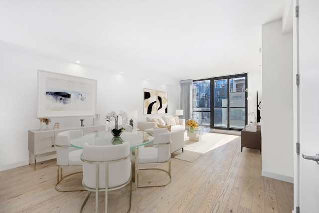 dining room with floor to ceiling windows, light wood-style flooring, and baseboards