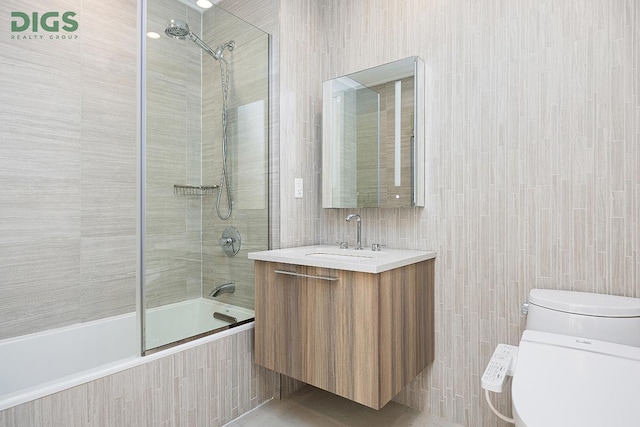 full bathroom featuring toilet, tiled shower / bath, tile walls, and vanity