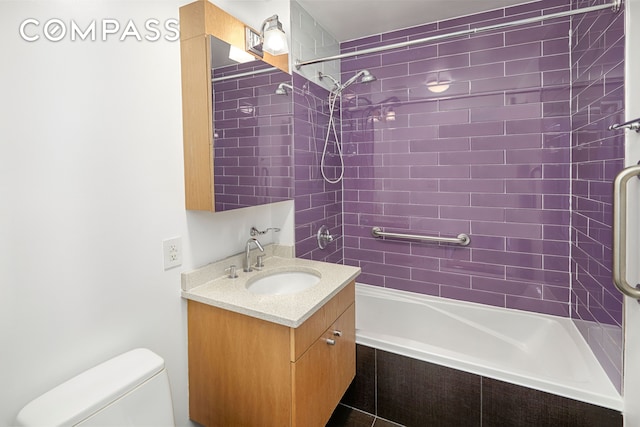 bathroom with toilet, vanity, and tiled shower / bath