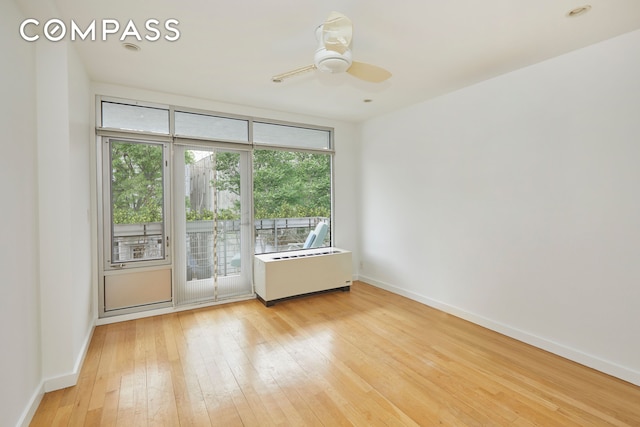 unfurnished room with ceiling fan, baseboards, radiator heating unit, and light wood-style floors