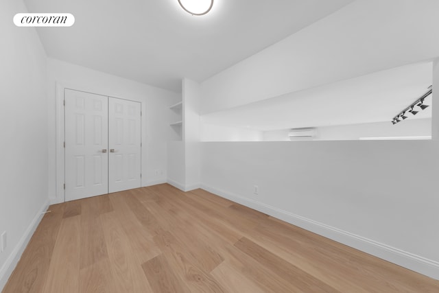 unfurnished bedroom featuring light wood finished floors, a closet, and baseboards