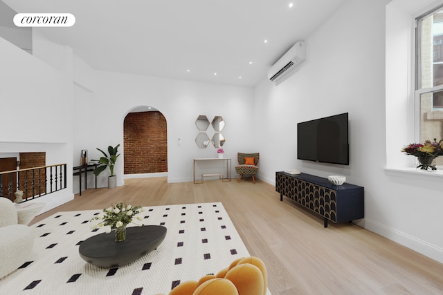 living area featuring wood finished floors, baseboards, visible vents, a wall mounted AC, and arched walkways