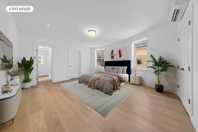 bedroom with a wall mounted AC, light wood finished floors, multiple windows, and recessed lighting