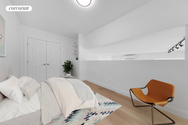 bedroom featuring light wood-type flooring, a closet, baseboards, and rail lighting
