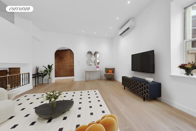 living area featuring a wall mounted air conditioner, wood finished floors, arched walkways, recessed lighting, and baseboards