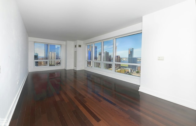 empty room with a view of city, baseboards, and hardwood / wood-style floors