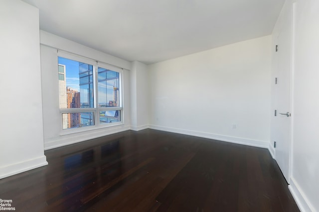 empty room featuring dark wood-style flooring and baseboards