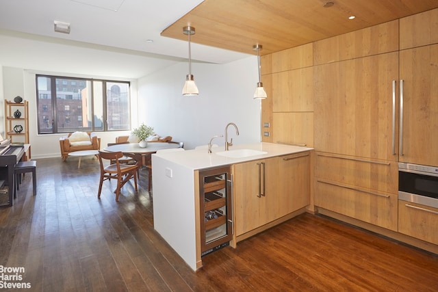 kitchen with wine cooler, oven, a peninsula, dark wood-style flooring, and a sink