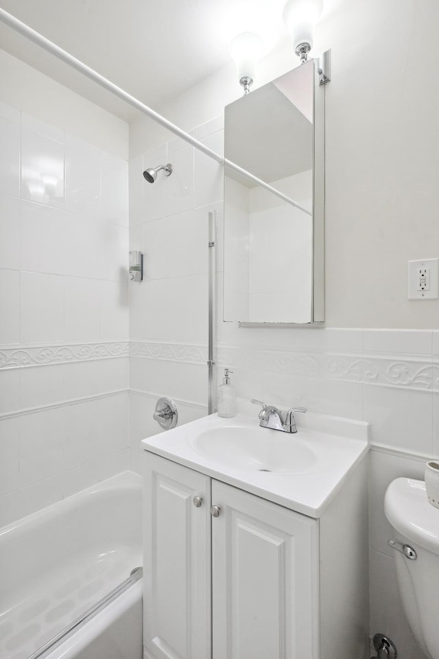bathroom featuring bathtub / shower combination, vanity, toilet, and tile walls