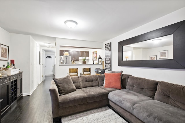 living area featuring baseboards, dark wood-type flooring, and a dry bar