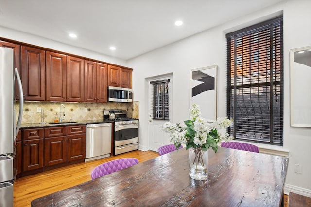 kitchen featuring appliances with stainless steel finishes, a sink, light wood finished floors, tasteful backsplash, and recessed lighting