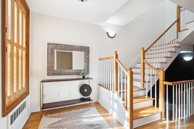 stairway featuring radiator heating unit, wood finished floors, and baseboards