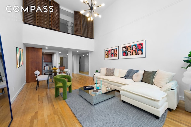 living room featuring baseboards, a high ceiling, a chandelier, and hardwood / wood-style floors