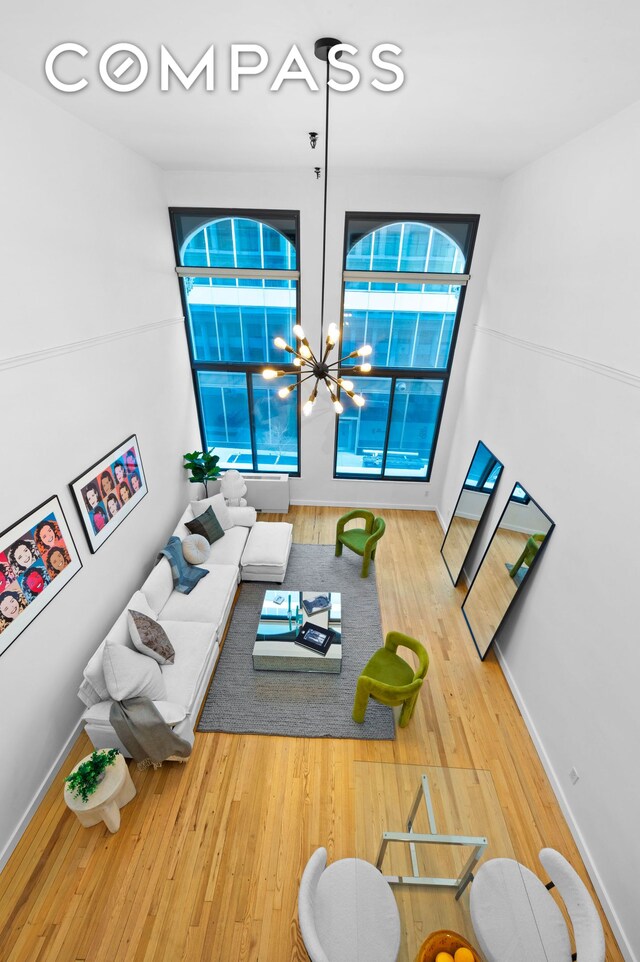 living room featuring baseboards, wood finished floors, and a notable chandelier