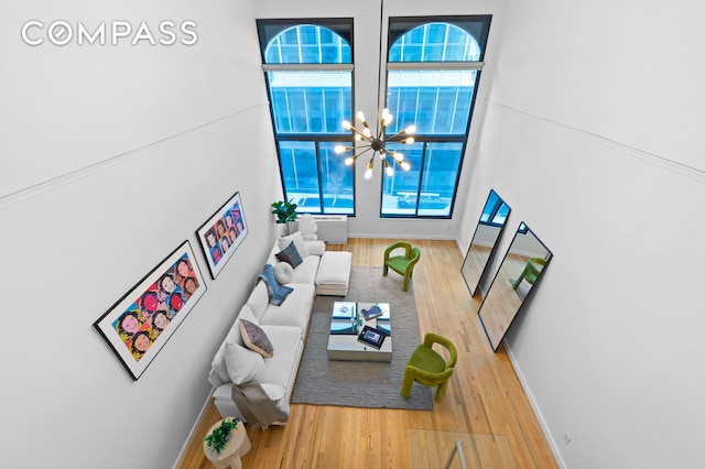 living room with baseboards, a high ceiling, wood finished floors, and a notable chandelier