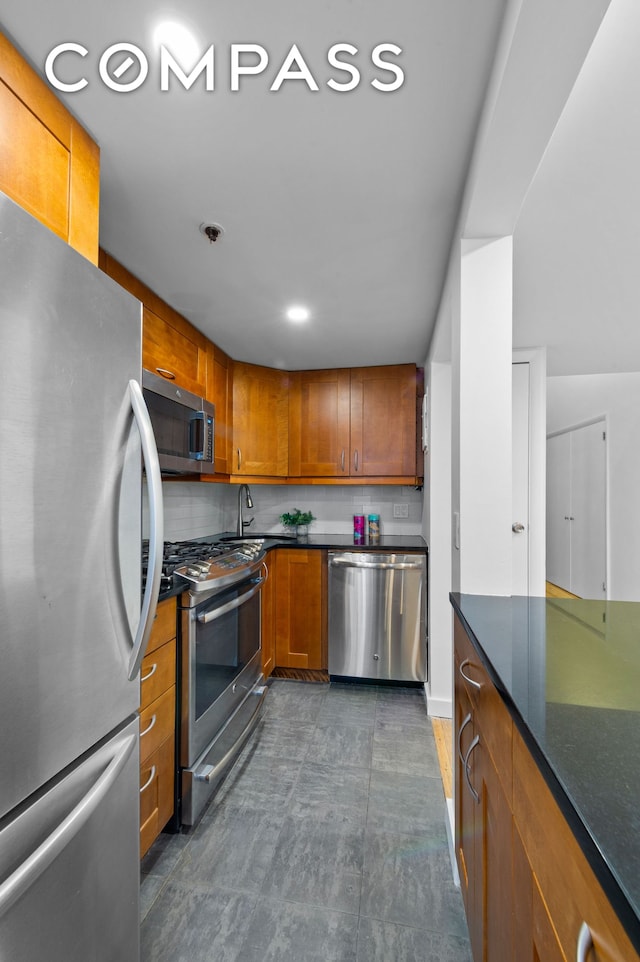 kitchen featuring appliances with stainless steel finishes, brown cabinetry, dark countertops, and decorative backsplash