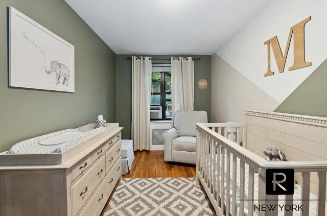 bedroom with a crib and light wood-style flooring