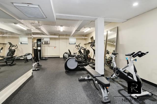 workout area with a baseboard heating unit, visible vents, and baseboards