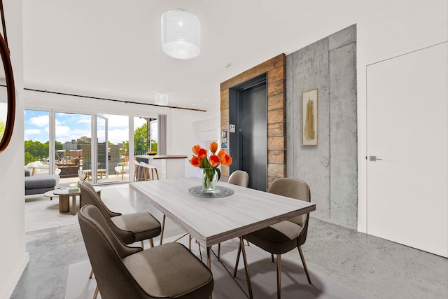 dining space featuring finished concrete flooring and elevator