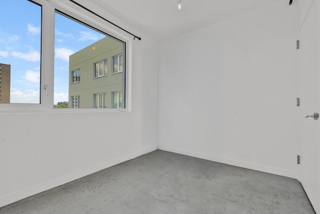 spare room featuring concrete floors and baseboards