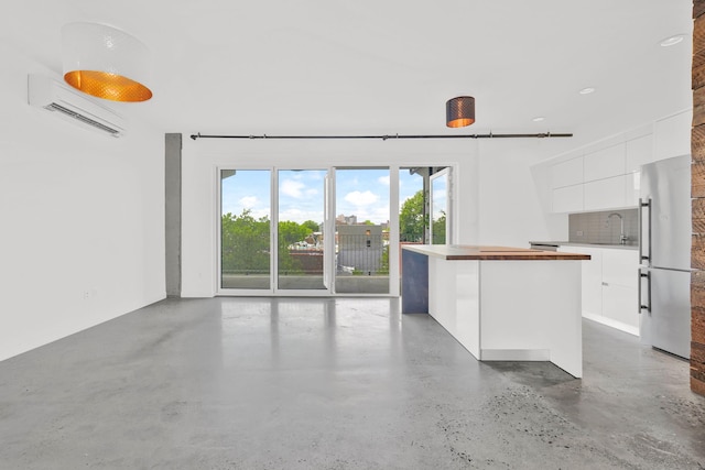 unfurnished living room with a sink, a wall mounted air conditioner, and finished concrete floors