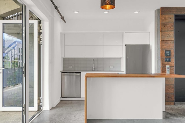 kitchen featuring white cabinetry, appliances with stainless steel finishes, backsplash, modern cabinets, and finished concrete floors