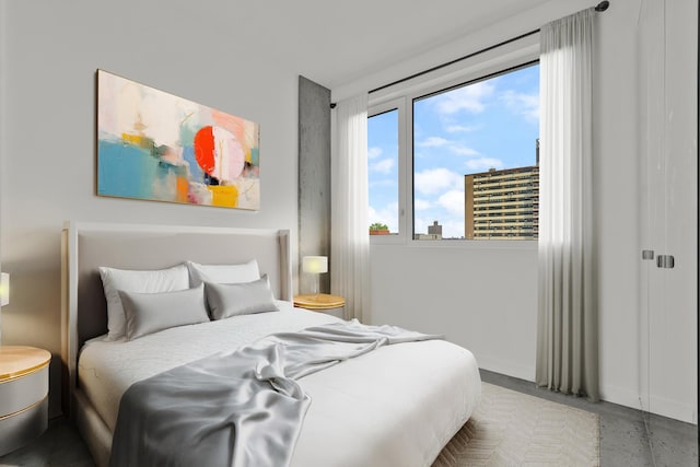 bedroom with finished concrete floors and baseboards