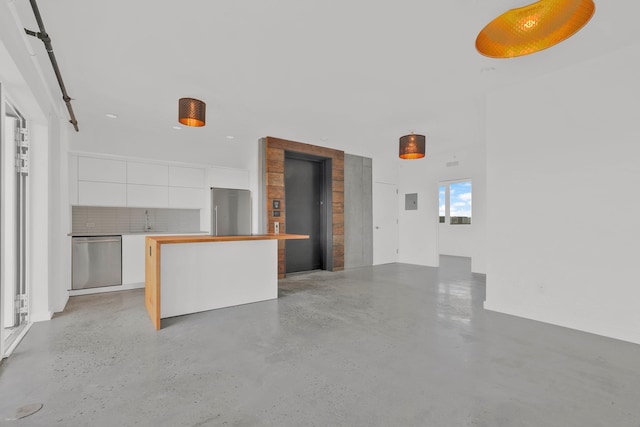 kitchen featuring concrete floors, a sink, stainless steel appliances, white cabinetry, and modern cabinets