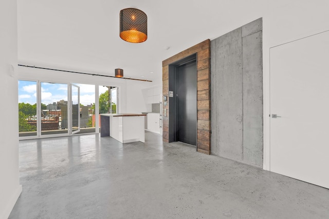 unfurnished living room with elevator and concrete floors