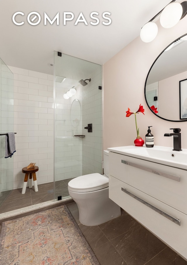 bathroom featuring vanity, a shower stall, and toilet