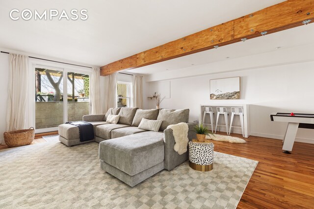 living room with beamed ceiling, baseboards, and wood finished floors