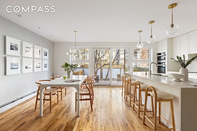 dining space featuring a baseboard heating unit and light wood-type flooring