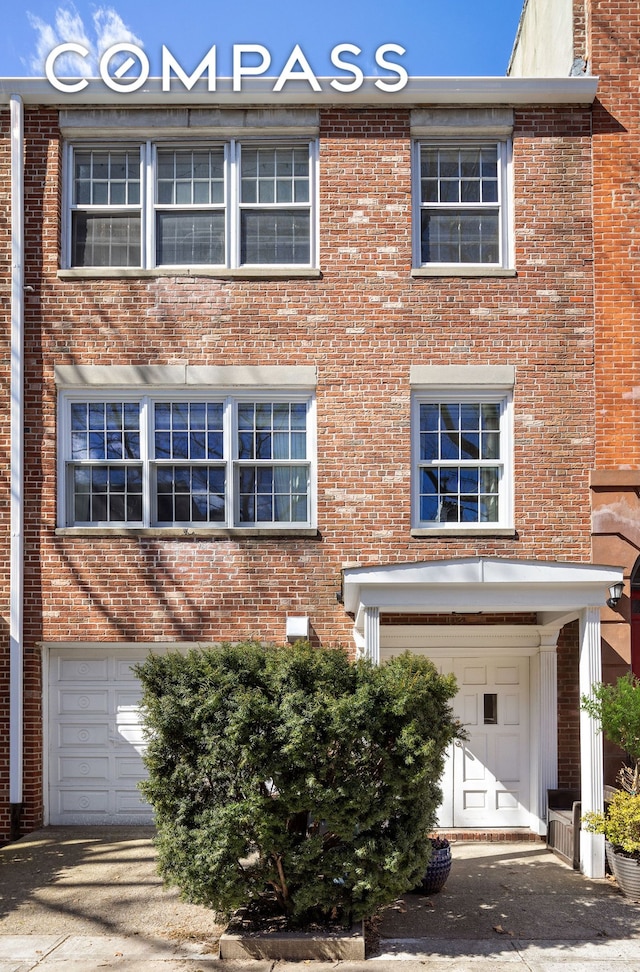 townhome / multi-family property with brick siding and a garage