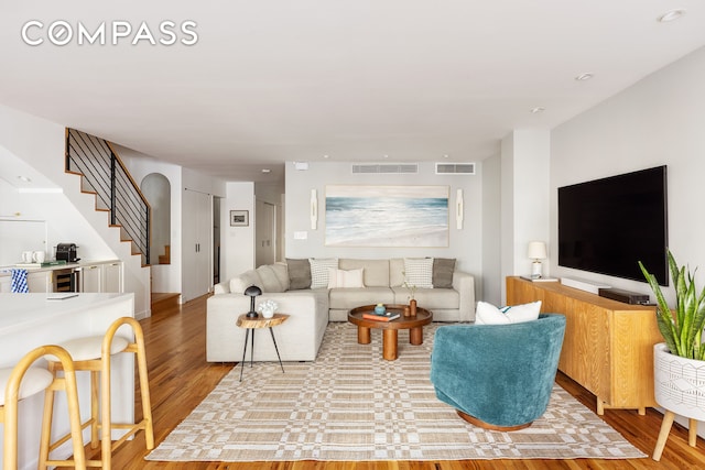 living room featuring stairway, wood finished floors, and visible vents