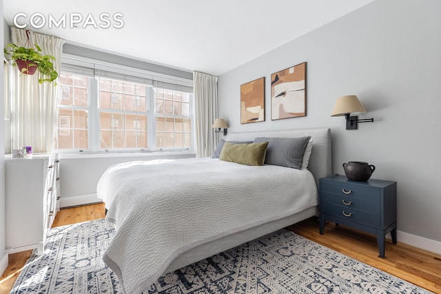 bedroom with light wood-style floors, baseboards, and a baseboard radiator