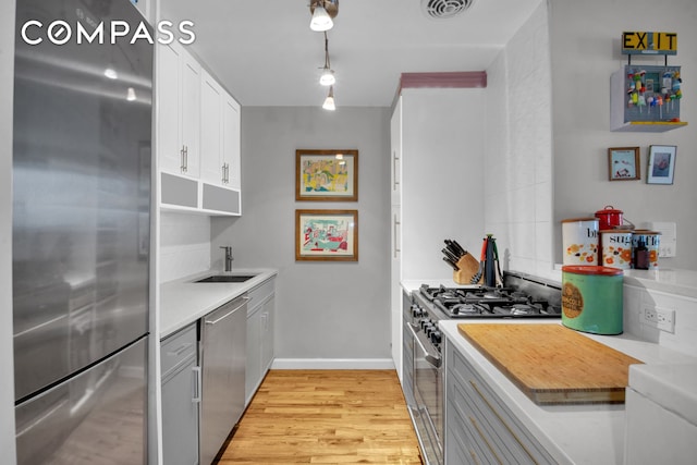 kitchen featuring visible vents, a sink, stainless steel appliances, light countertops, and light wood-type flooring