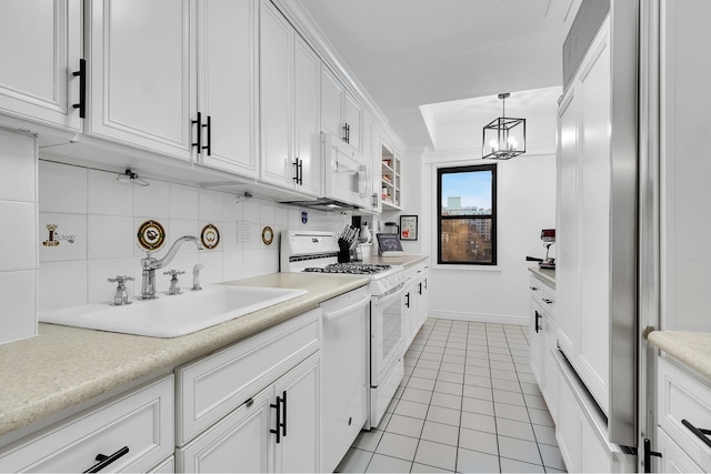 kitchen with white appliances, a sink, decorative backsplash, light countertops, and white cabinetry