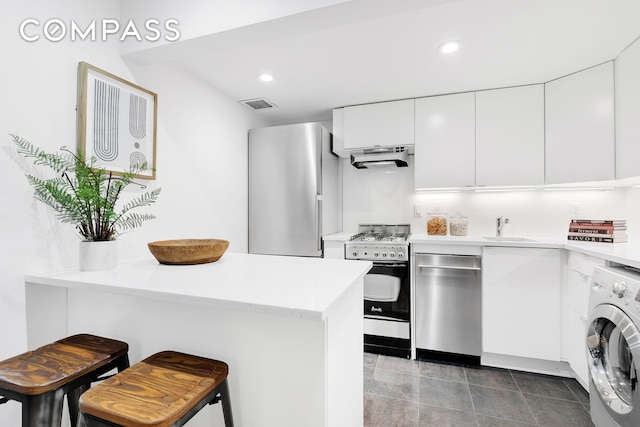 118 Suffolk St Unit 3Ab, New York City, NY 10002 - kitchen featuring stainless steel appliances, washer / dryer, under cabinet range hood, a sink, and white cabinets