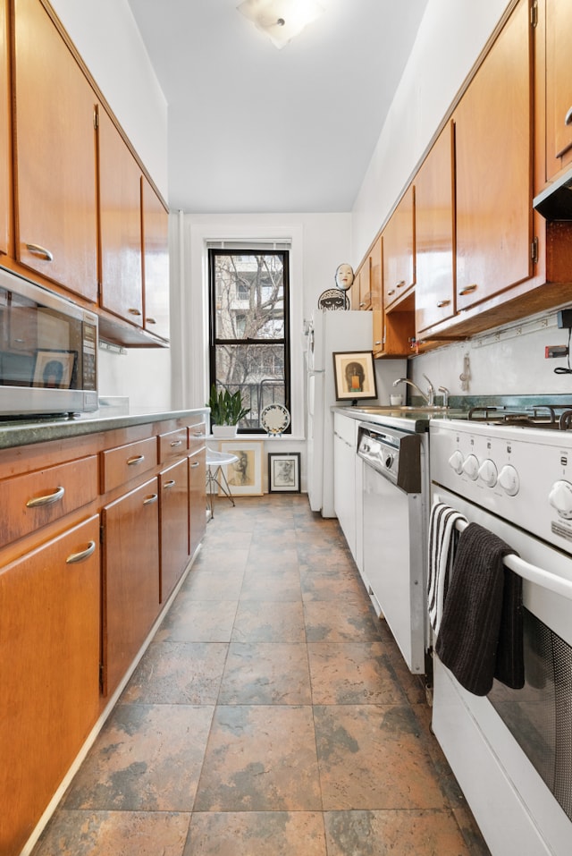 131 E 29th St, New York City, NY 10016 - kitchen with white appliances, dark stone finish flooring, and brown cabinets