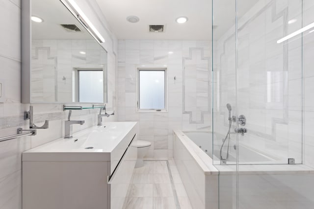 bathroom with visible vents, vanity, toilet, and tile walls