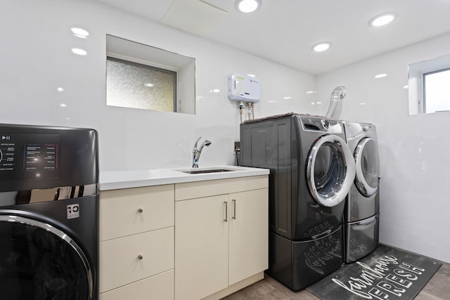 clothes washing area with a sink, water heater, recessed lighting, cabinet space, and washing machine and clothes dryer