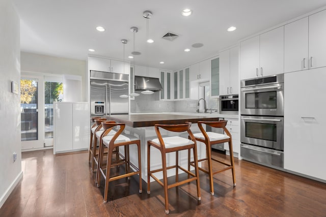 kitchen with visible vents, a sink, under cabinet range hood, appliances with stainless steel finishes, and a warming drawer