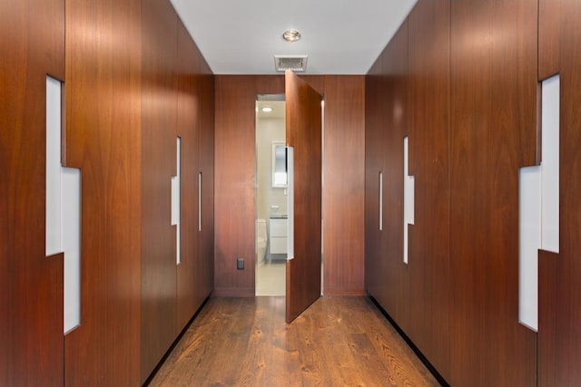 hallway featuring visible vents, wood finished floors, and wood walls