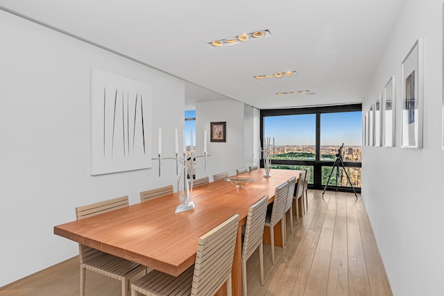 dining area featuring light wood-type flooring and a wall of windows