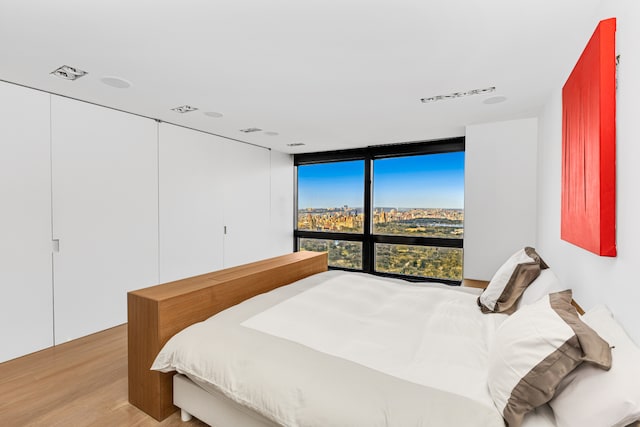 bedroom with expansive windows and light wood-style flooring
